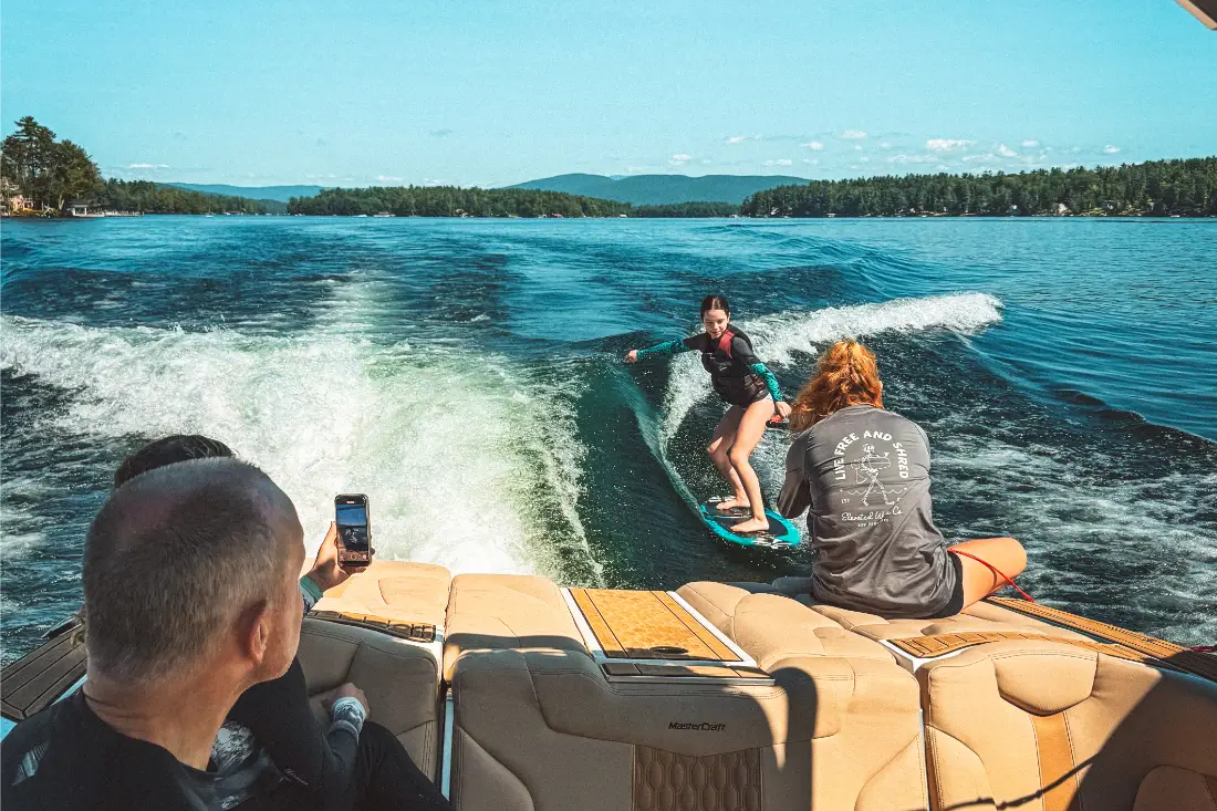 A family on a private water sports charter on Lake Winnipesaukee while the daughter learns to surf.